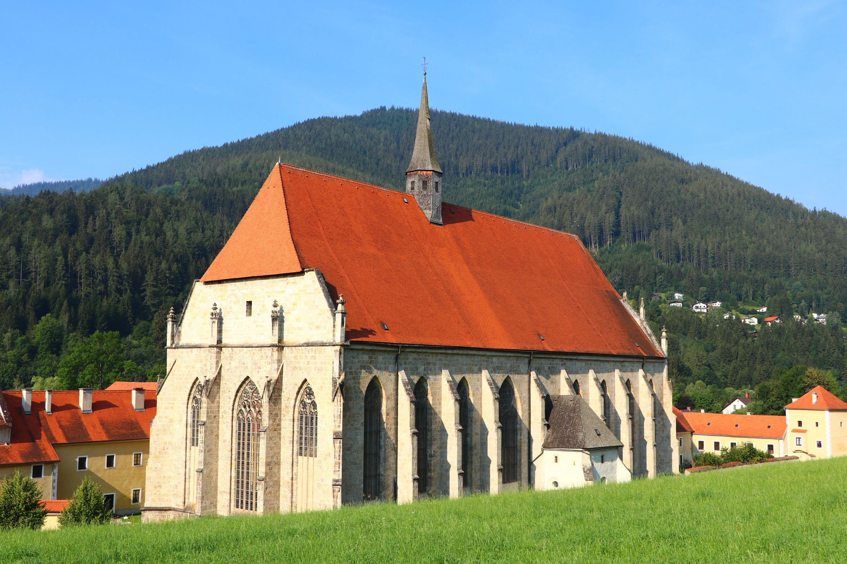 Das Neuberger Münster mit rotem Dach und Dachreiter vor den bewaldeten Bergen